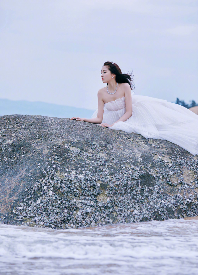 关晓彤出席今晚金鸡奖红毯的造型图曝光，穿珍珠白浪花裙在厦门海边拍摄大片，大秀雪白香肩和迷人锁骨，气质出尘似仙女。