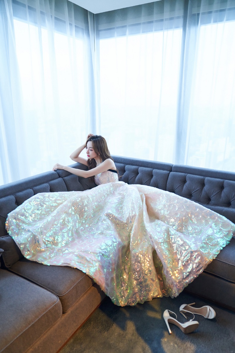 她倚靠在沙发上，一袭长裙美丽梦幻。