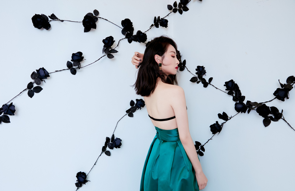 她靠在墙边，与手工黑玫瑰花藤形成了一幅完美的画面。