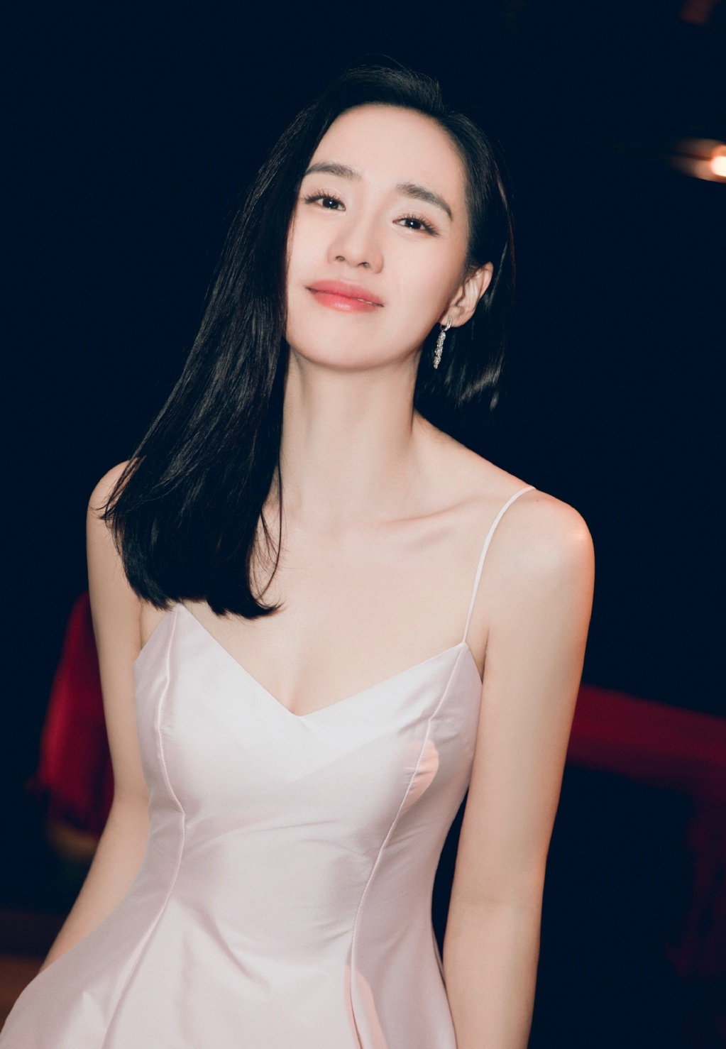她一袭粉裙飘逸又美又仙，长发披肩气质温婉动人。