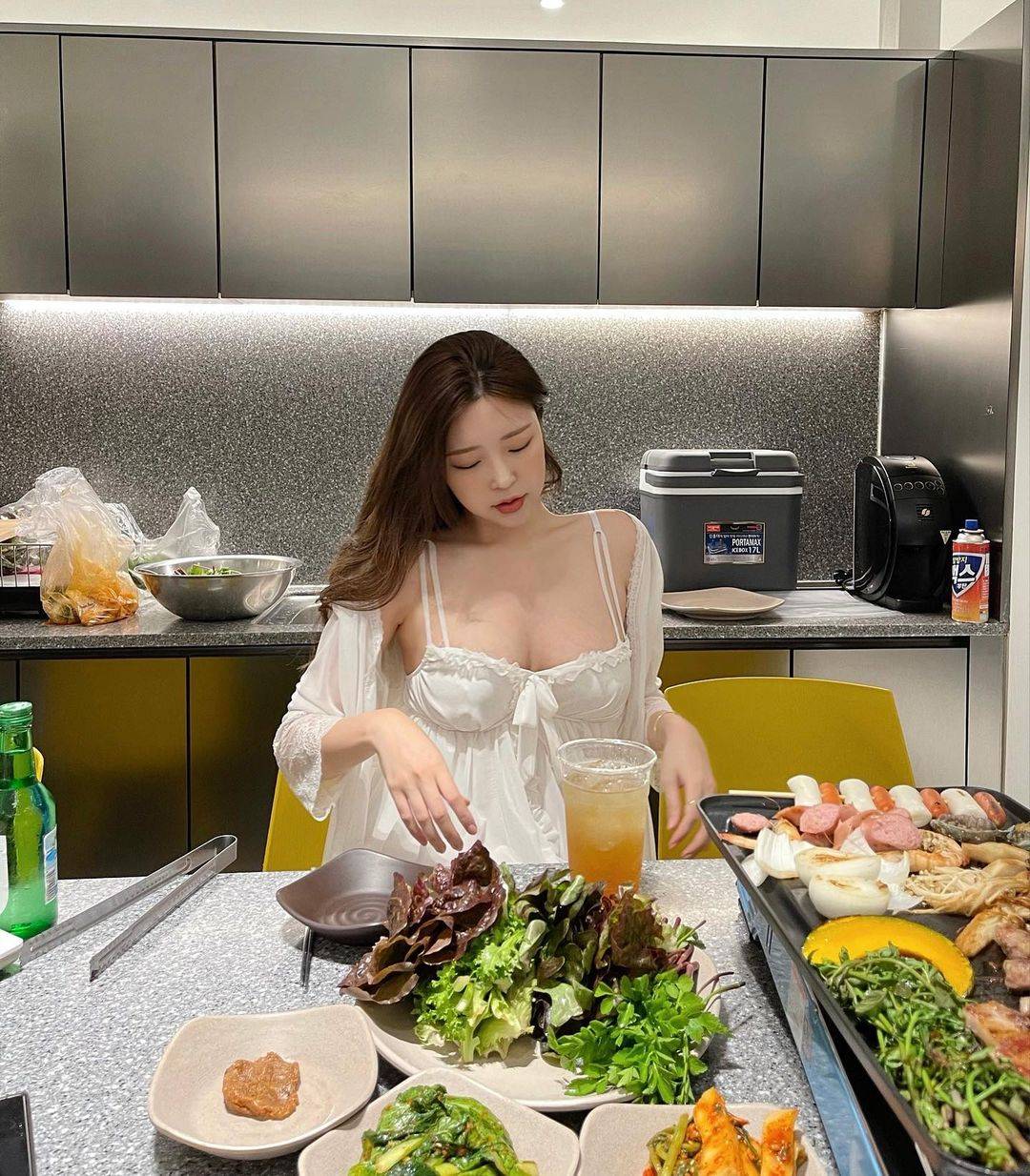 韩国主播米娜近日在社交平台发布一组照片，照片中的她正在吃烤肉，穿着白色睡衣大秀傲人身材的同时，还不忘对镜自拍，十分撩人。